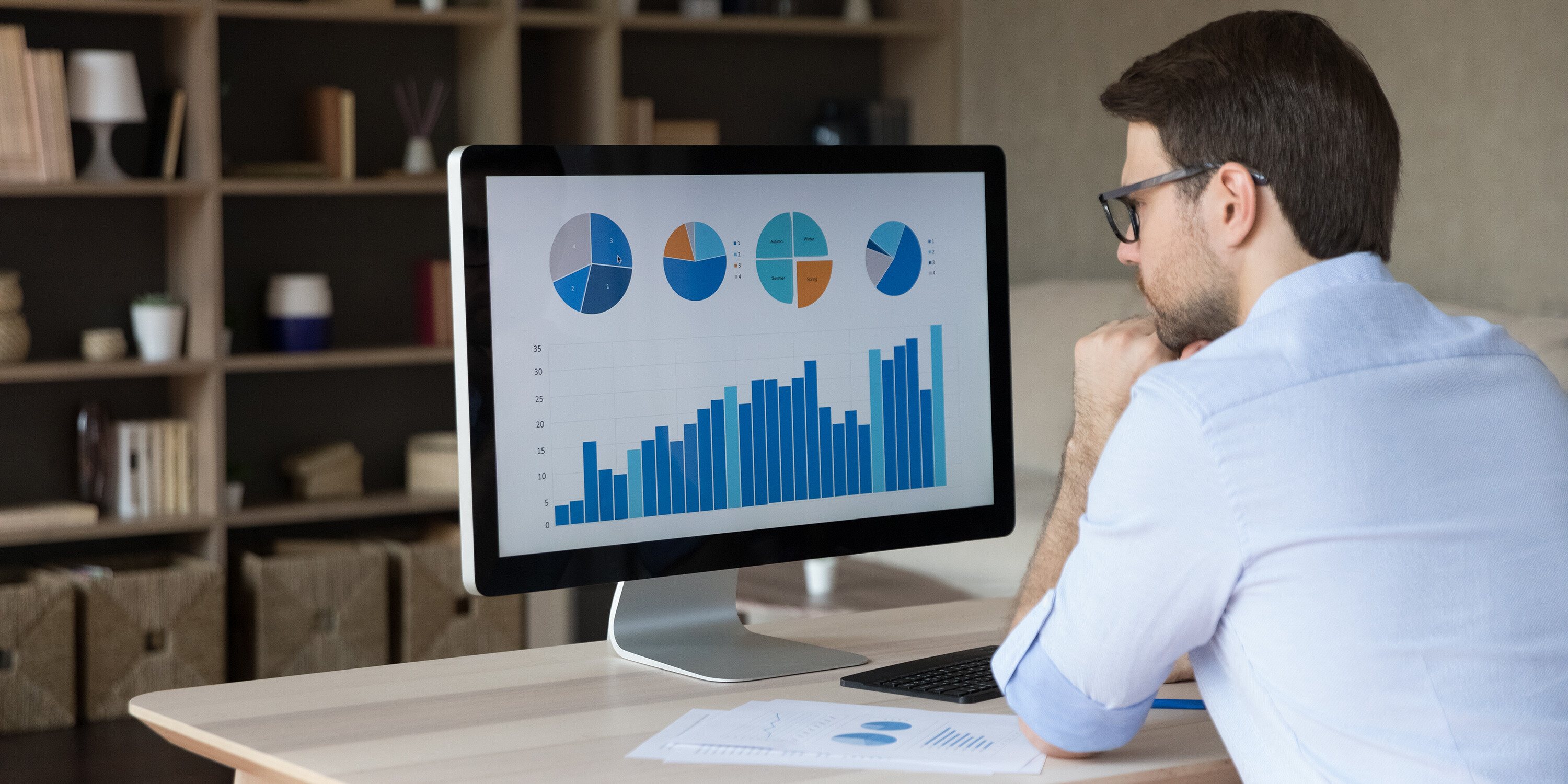 Man looking at charts of IT expenditure, assessing IT cost reduction strategies